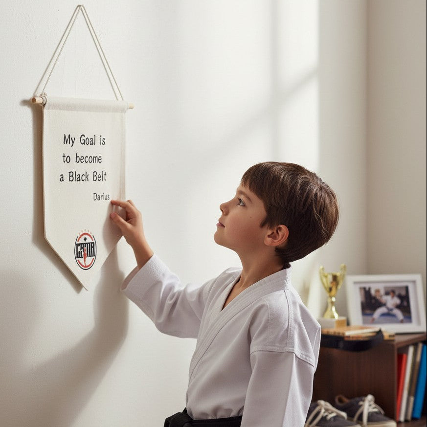 Child in a martial arts uniform looking at a banner on a wall.