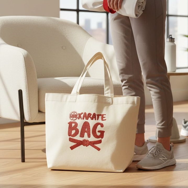 Person holding a rolled-up mat next to a tote bag with 'Karate Bag' text in a home setting.