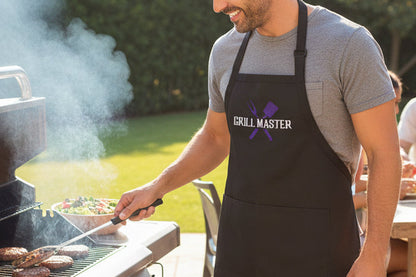 Man grilling outdoors with a group of people sitting at a table in the background